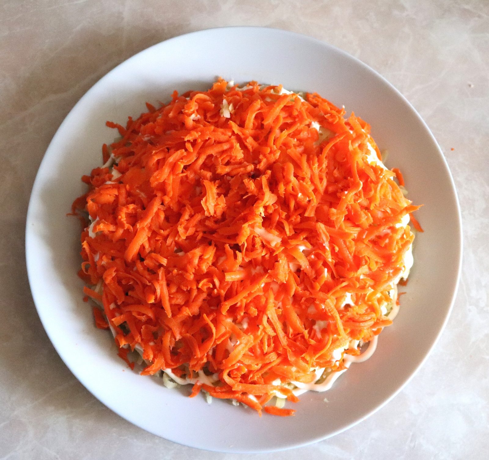 Step 4. The next layer is carrots on the same grater + mayonnaise. Dressed herring (seledka pod shuboy)