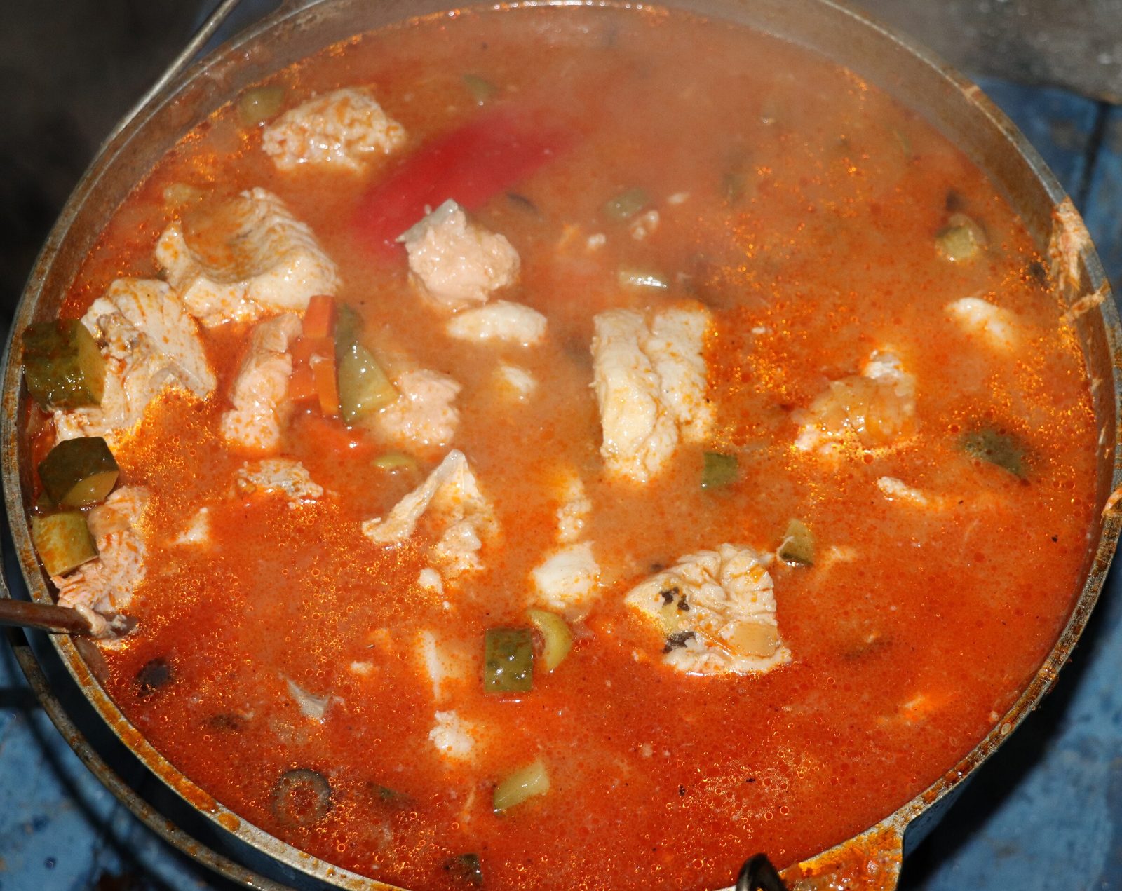 Step 8. When the carrots are ready, use a spoon or spatula to push the vegetables to. Fish solyanka in a kazan over the fire