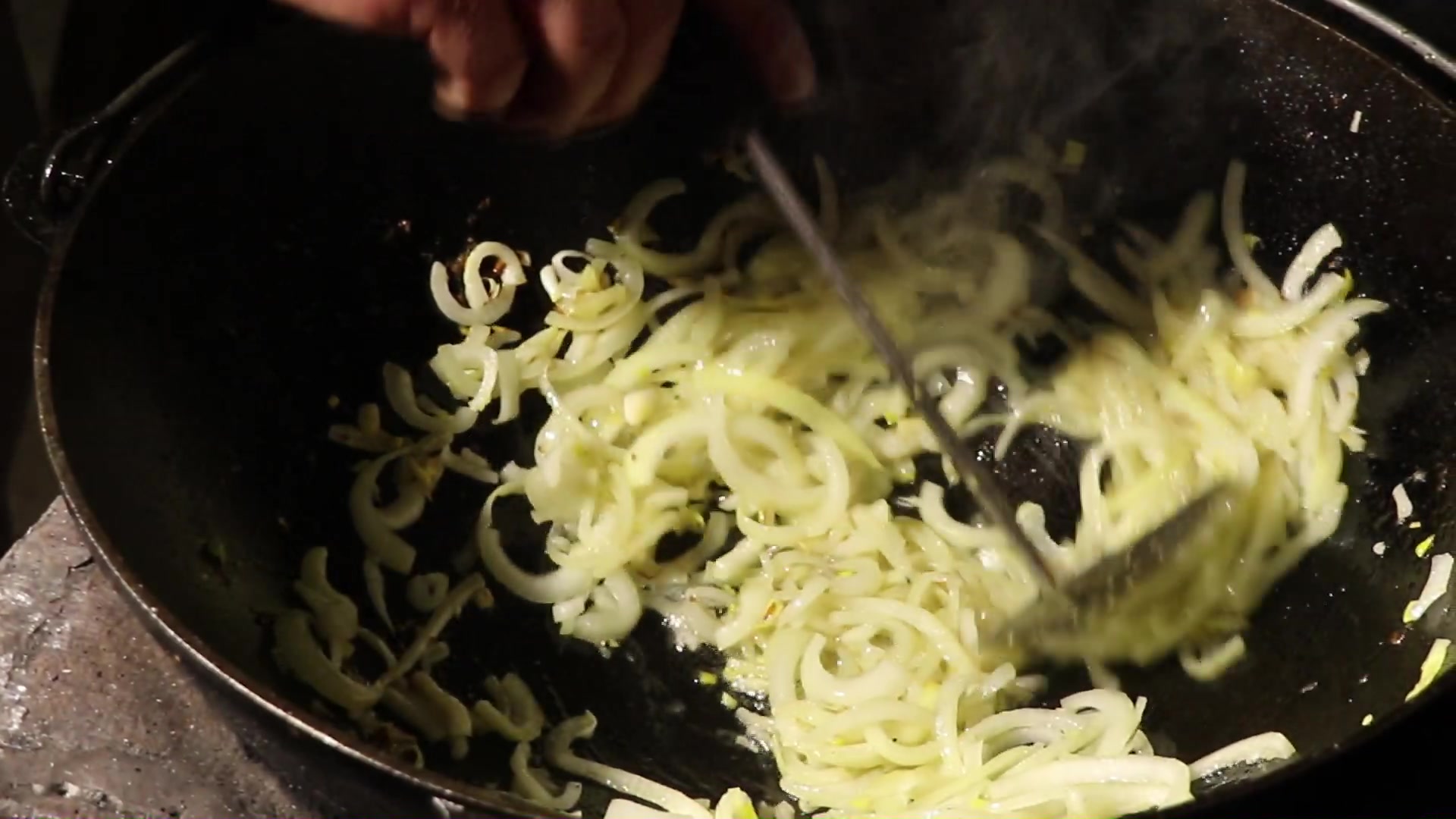 Step 4. Cut the onion into half rings and place in a preheated cauldron. Fried potatoes in a kazan over the fire