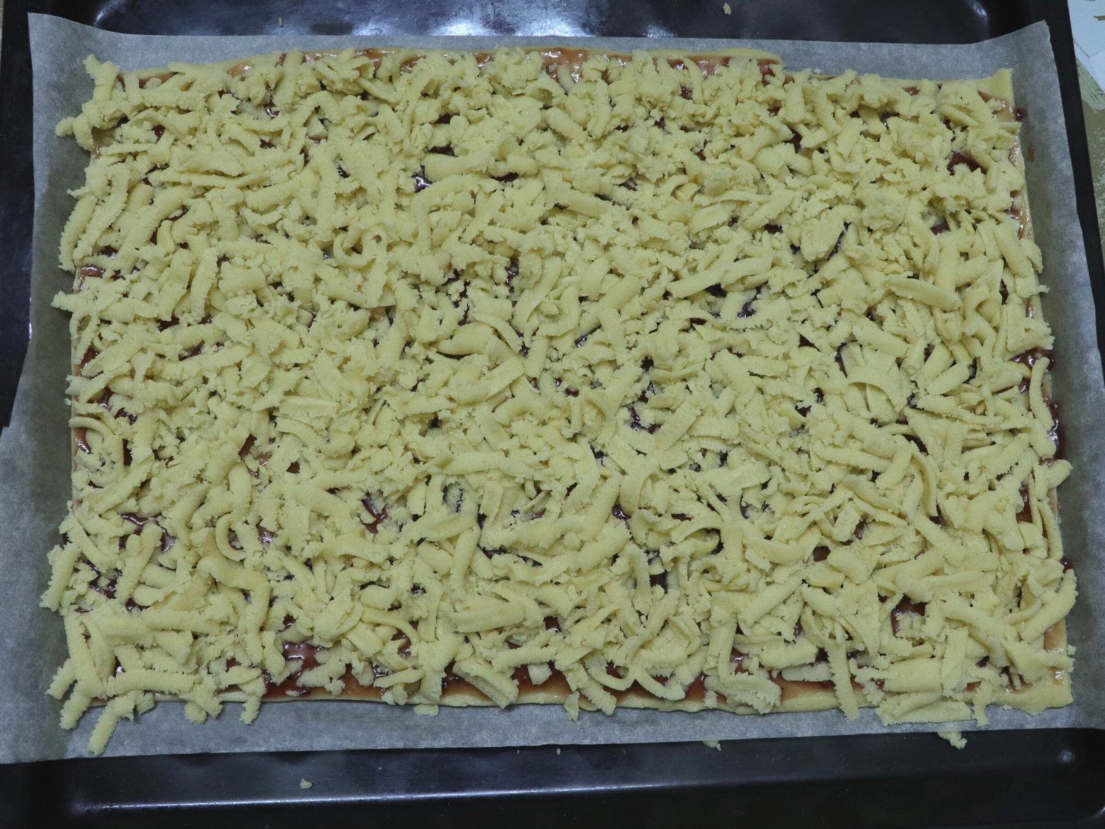 Step 8. Rub the remaining dough on top of the jam using a coarse grater. Grated shortcrust jam tart