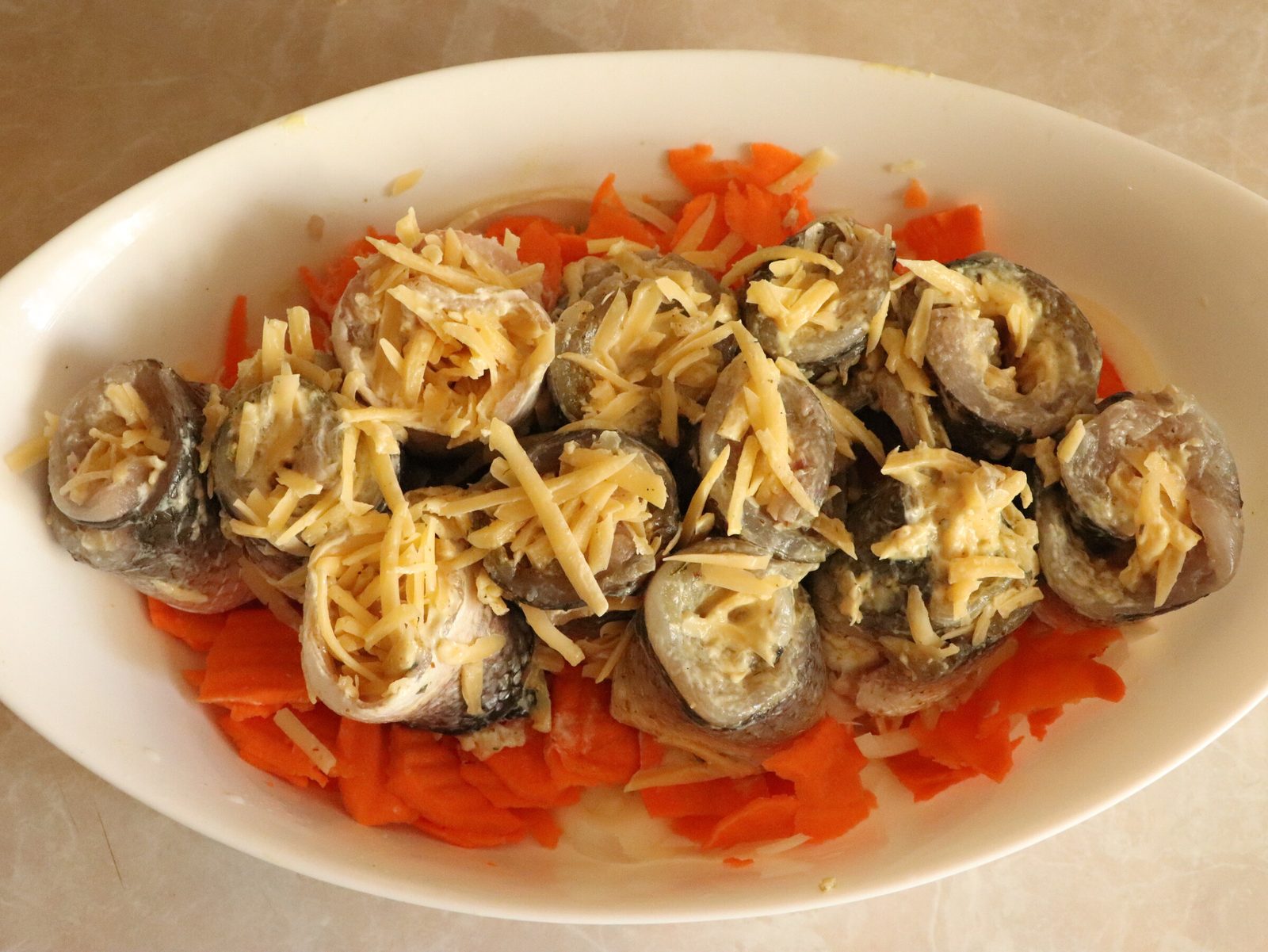 Step 5. Sprinkle with grated hard cheese and roll up. Grey mullet rolls with cheese on a bed of