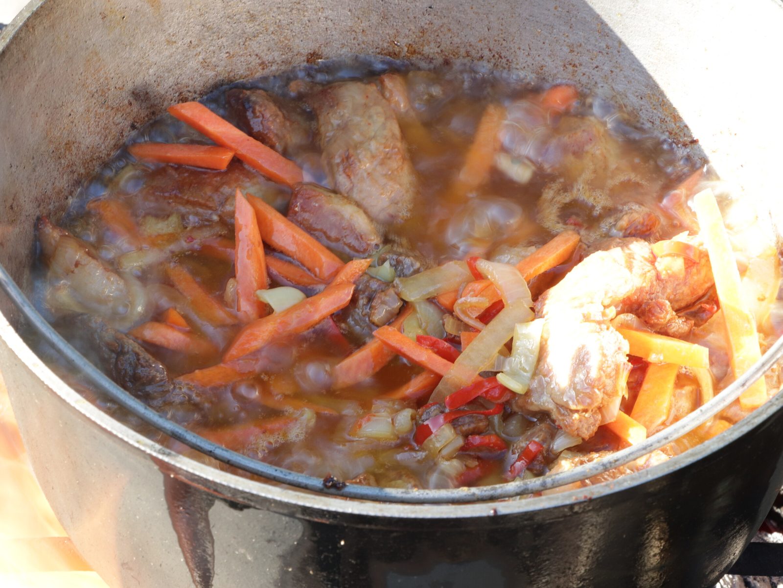 Step 5. When the carrots become soft, add the tomatoes. Lagman in a kazan over the fire
