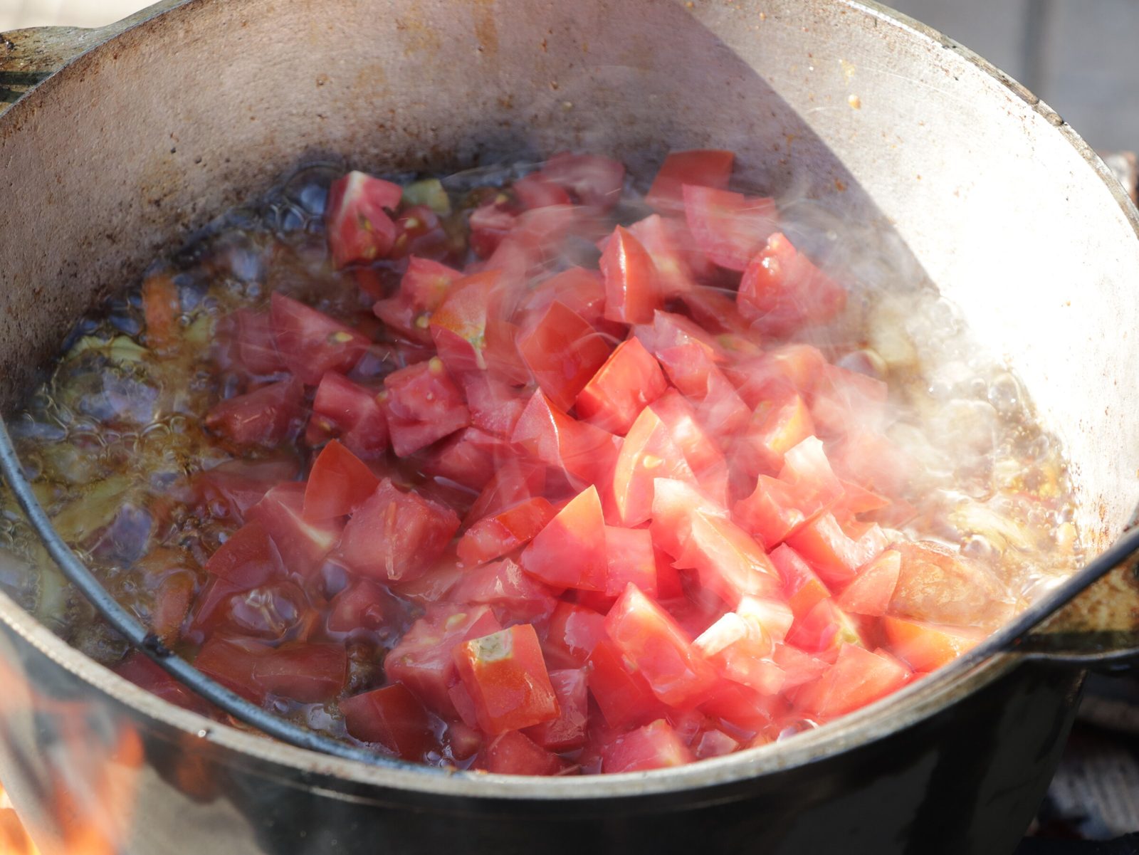Step 6. When the tomatoes are cooked, add water to the cauldron, cover it with a lid. Lagman in a kazan over the fire