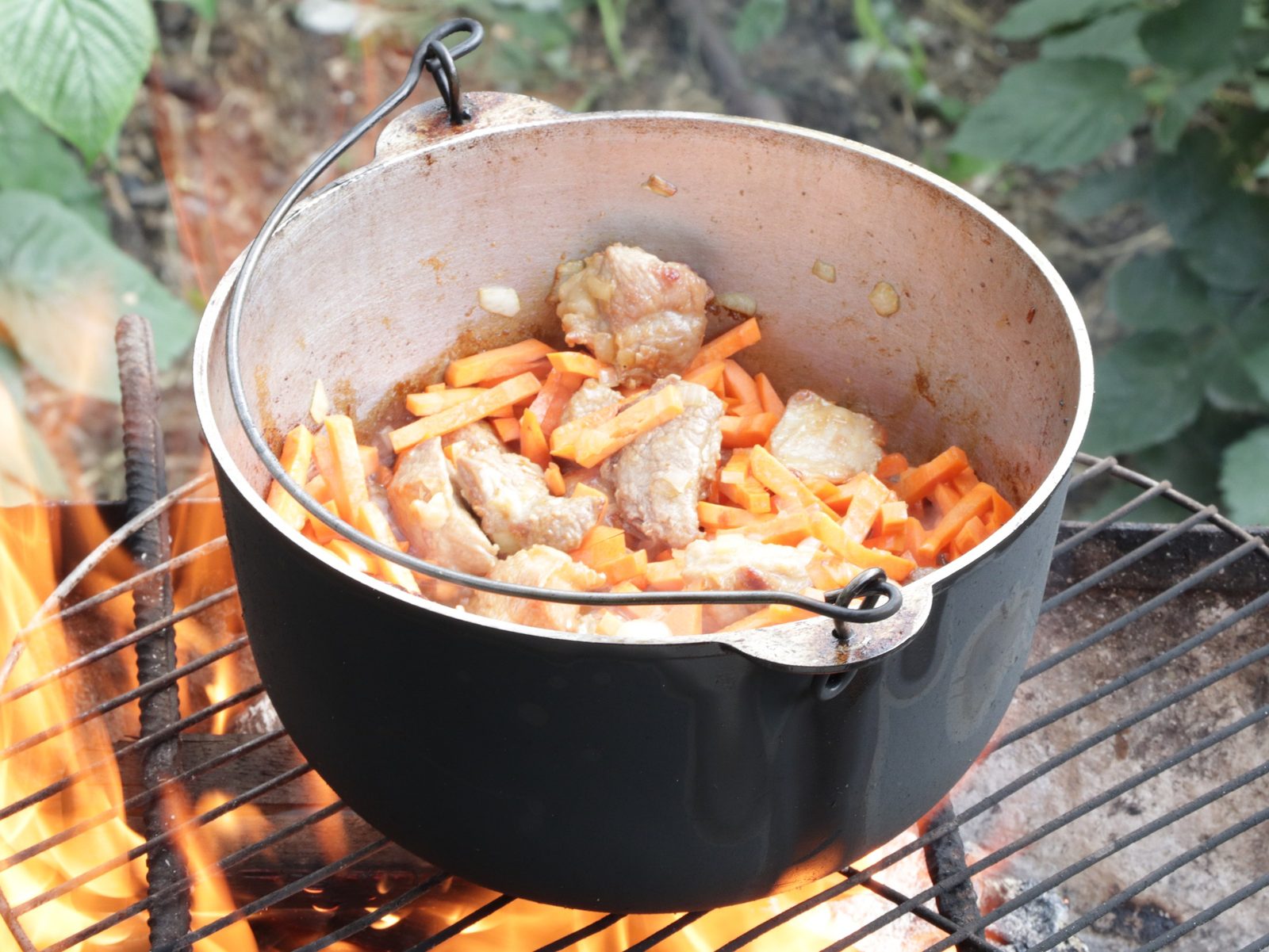 Step 6. When the carrots are ready, add water so that it covers the food by about 1 cm. Plov in a kazan over the fire
