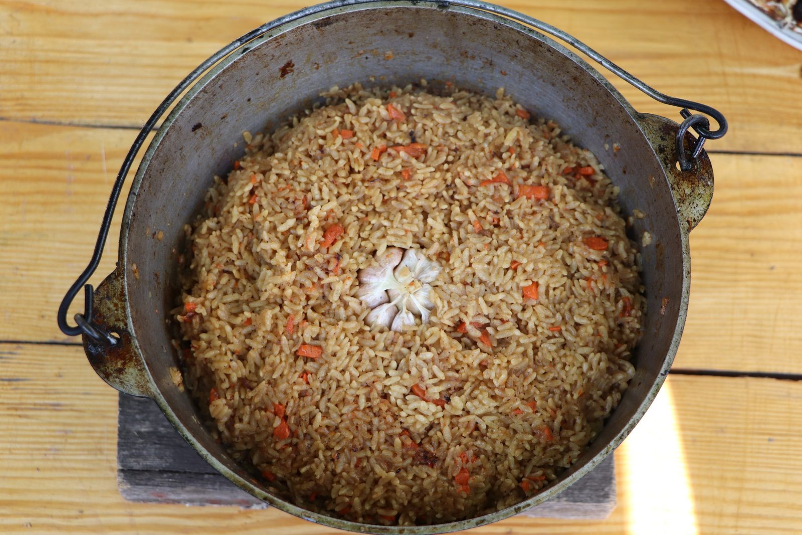 Step 8. At the end of cooking, add a whole head of garlic to the rice, after removing. Plov in a kazan over the fire